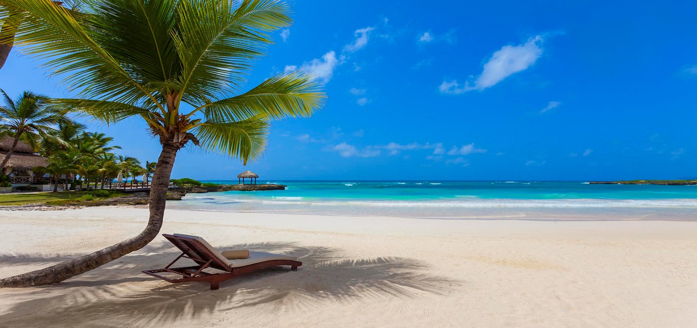 Punta Cana pristine beach with lounge chair under a single palm three with turquoise ocean water