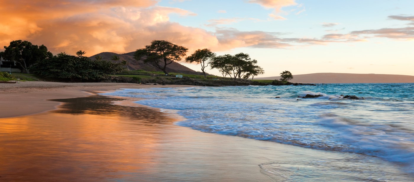 Wailea beach with wet sand with the orange sky reflected in the sand